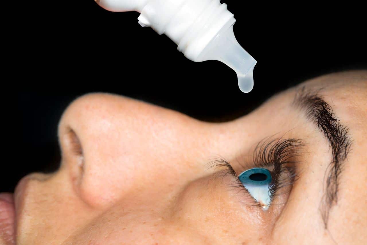 Woman adds eye drops to her sore, dry eyes